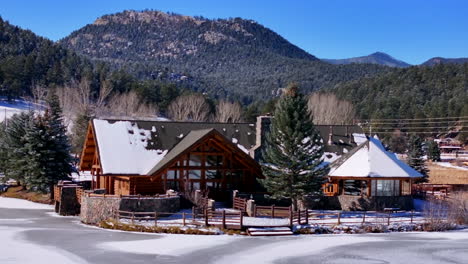 First-snow-ice-frozen-covered-white-Evergreen-Lake-House-Rocky-Mountain-landscape-scene-morning-front-range-Denver-aerial-cinematic-drone-Christmas-ice-skating-hockey-blue-sky-backward-motion