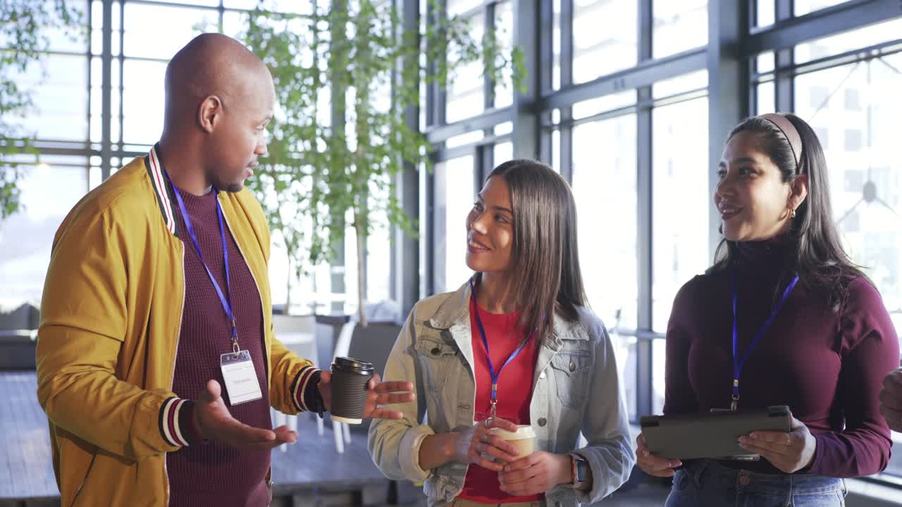 Greeting sparking Diverse coworkers tapping tablet by windows laughing and inviting senior feedback