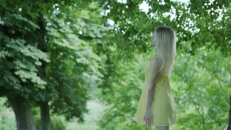 mujer con vestido amarillo bailando junto al árbol en el parque de verano