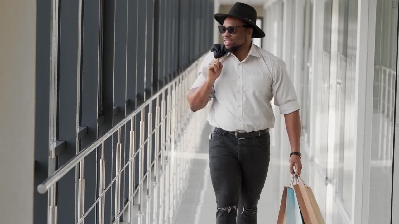 Uomo africano che cammina lungo il corridoio dopo aver fatto shopping.