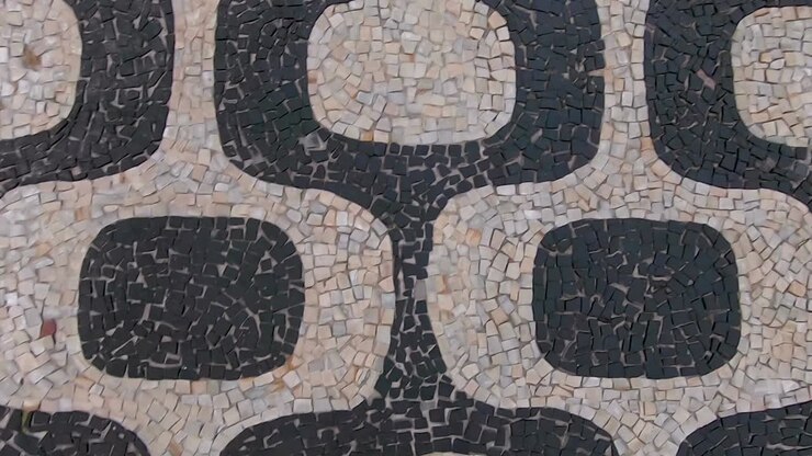 Slow motion forward moving top down closeup view of the so called Portuguese pavement design in Ipanema, Rio de Janeiro, with typical shapes on the beach boulevard sidewalk