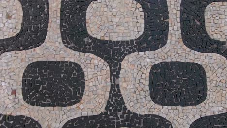 slow motion forward moving top down closeup view of the so called portuguese pavement design in ipanema, rio de janeiro, with typical shapes on the beach boulevard sidewalk