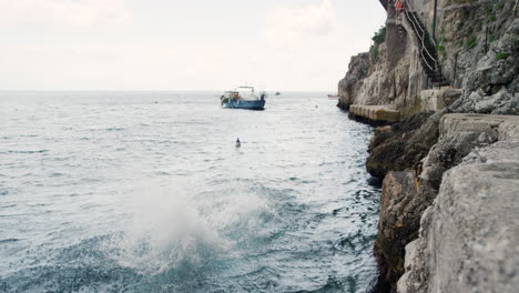 women jumping into the sea at a coastal cliffside