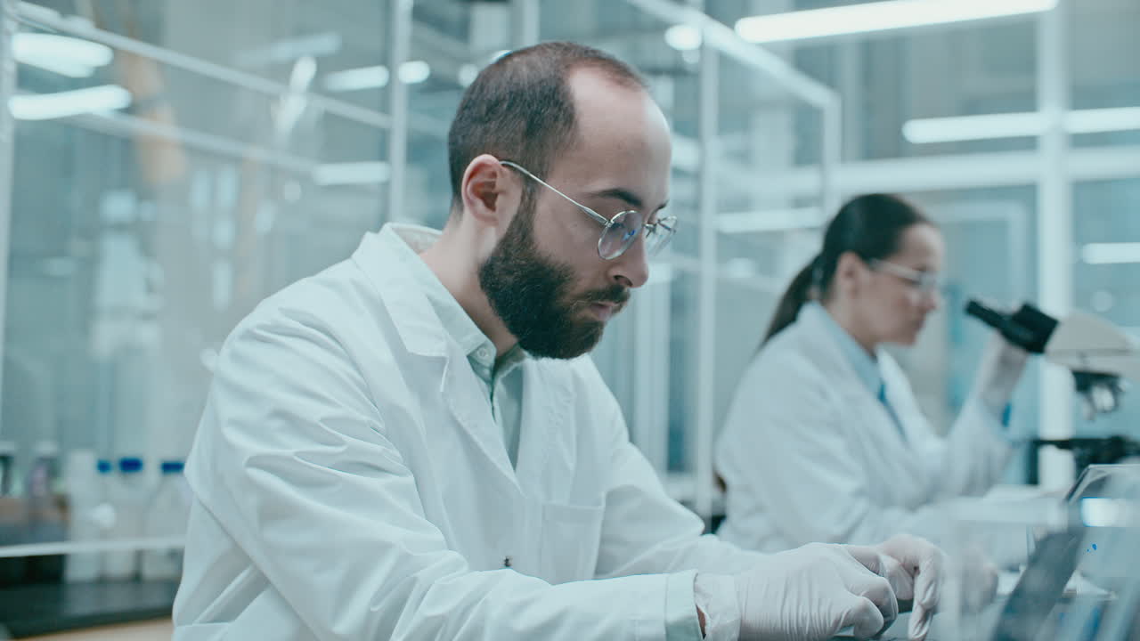 Male Scientist Typing Research Data on Laptop in Laboratory