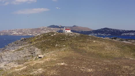 gaviotas volando alrededor de una pequeña iglesia en grecia