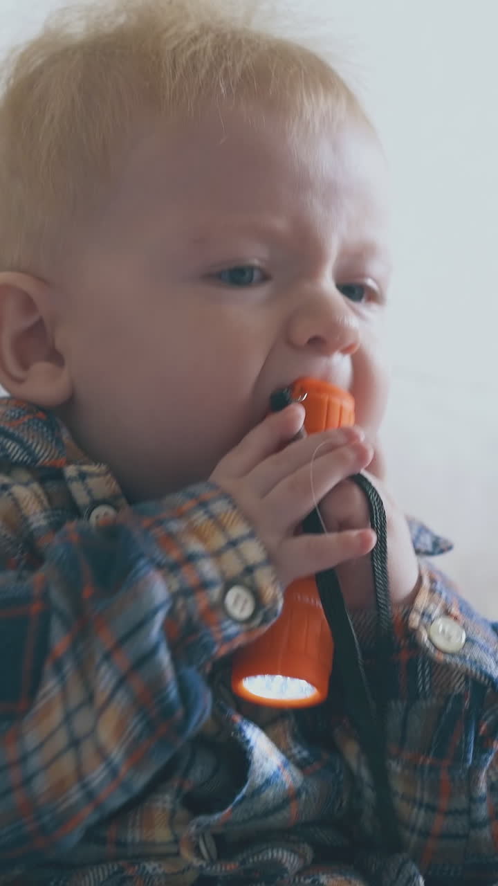 funny little baby nibbles flashlight crawling on large soft bed in light children room extreme close view