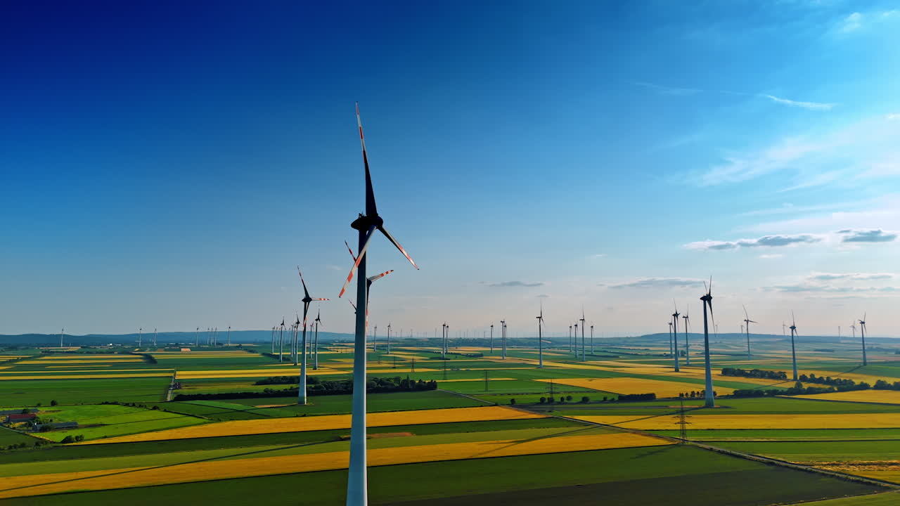 Vast countryside fields with wind farms. Production of sustainable energy. Aerial perspective