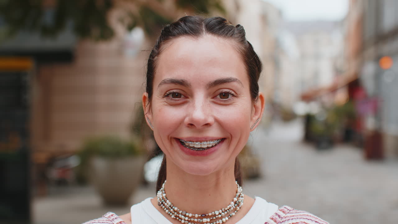 Close up portrait of happy caucasian young woman showing teeth with braces smiling laughing