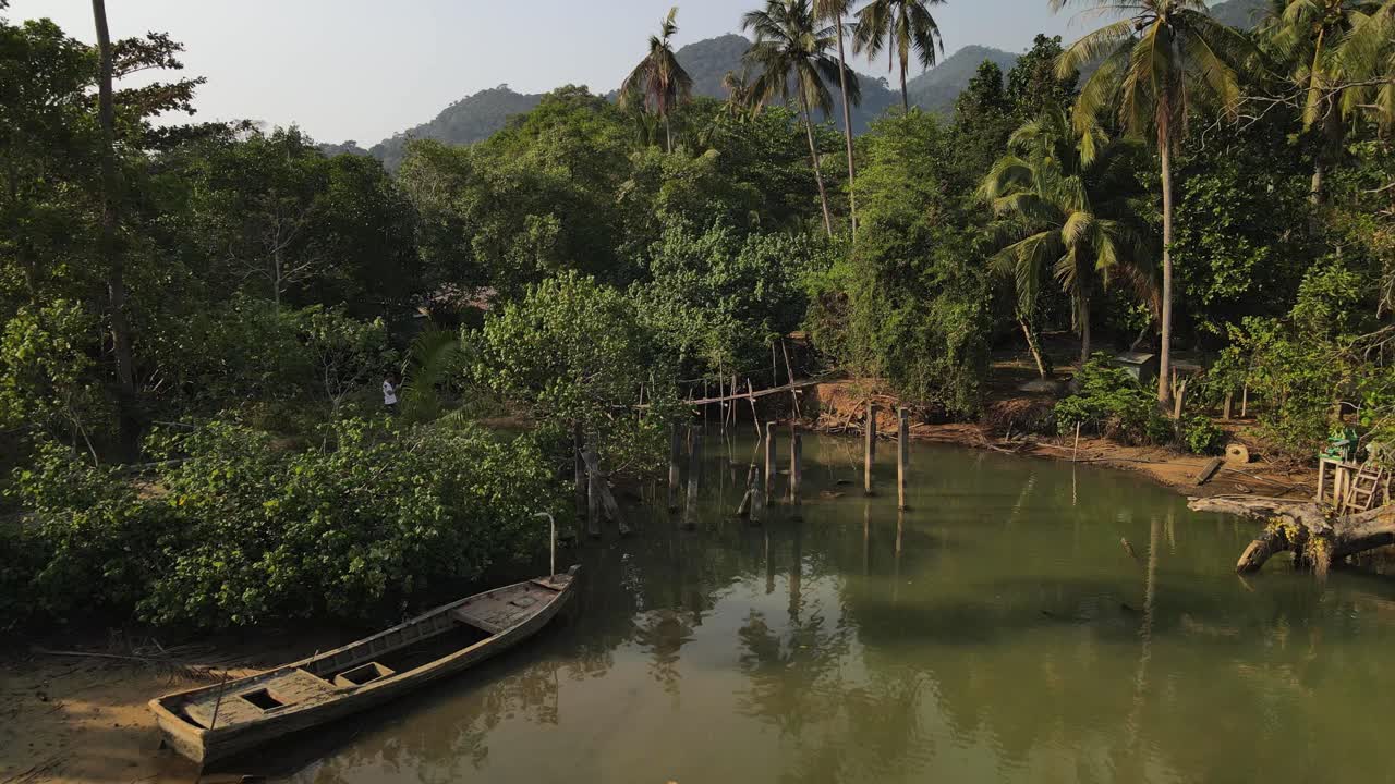 toma aérea inversa de un puente de madera y un bote en la selva tropical de koh chang, tailandia