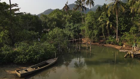 aerial reverse shot of a wooden bridge and boat in the rainforest of koh chang, thailand