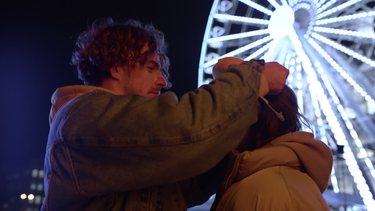 encantadora pareja teniendo cita en la calle urbana. hombre cuidadoso poniéndole sombrero a la mujer.