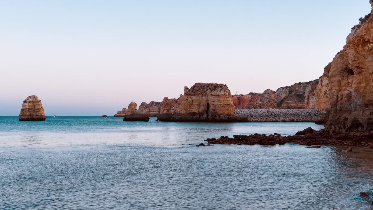 Solnedgang over kystklipper ved Lagos i Portugal