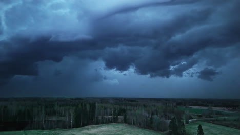 dark forest beneath dramatic clouds in a deep blue atmospheric light, evoking a moody scene.