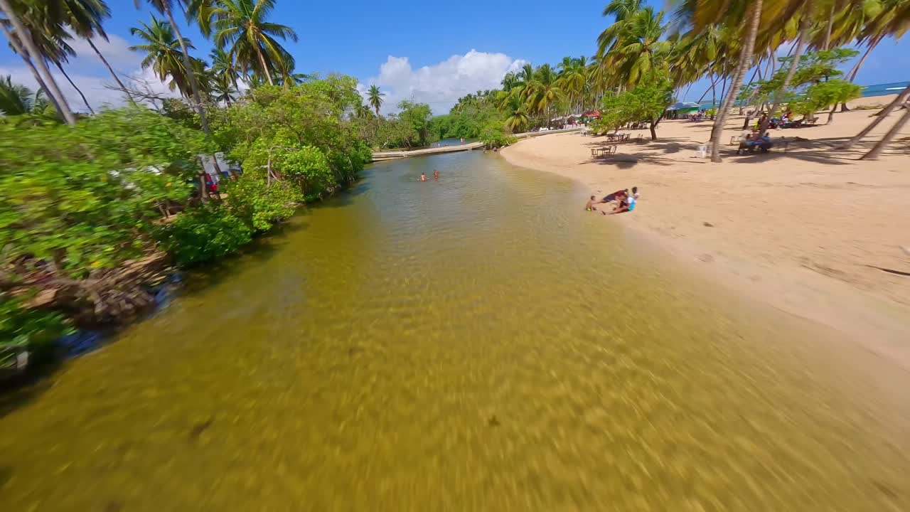vuelo de drones fpv a lo largo de la playa de arena y el río con niños jugando en arroyo saldo durante el verano
