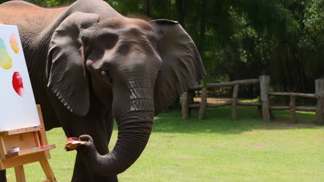 An elephant painting on a canvas with a paintbrush