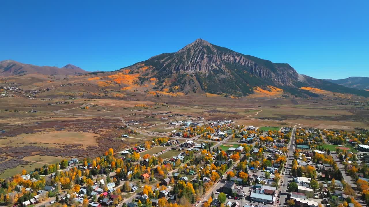 Mount Crested Butte mountain town ski resort Kebler Ohio Pass aerial drone Colorado morning vibrant Aspen Trees fall autumn auburn peak colors Gunnison National forest sunny blue sky backwards motion
