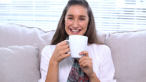 Brunette-sitting-on-sofa-drinking-her-cup