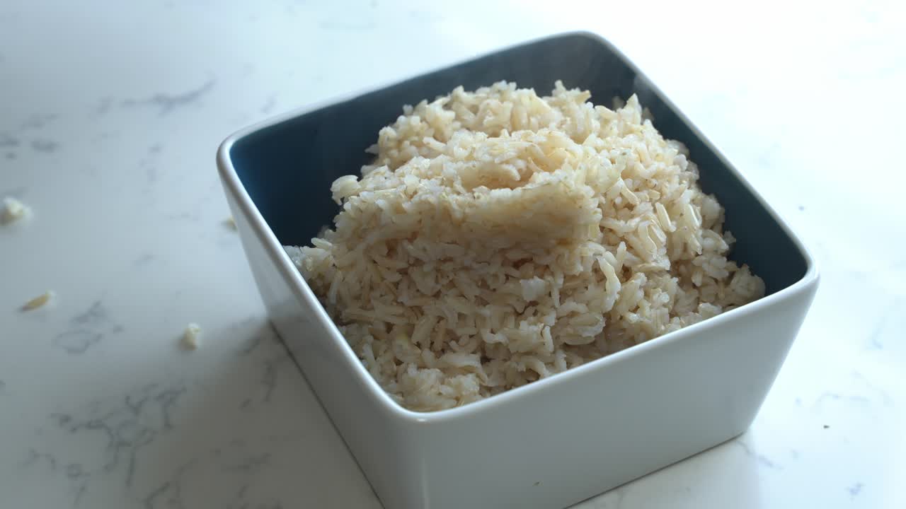 cerca de arroz marrón cocido que se coloca en un tazón para cocinar una comida dos latas de frijoles arroz plátano aguacate cebolla roja y cilantro