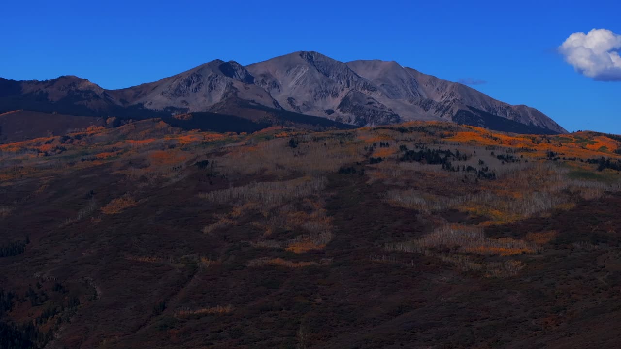 Mount Sopris mountain valley peak from Aspen Old Snowmass Village aerial drone Colorado fall autumn El Jebel Basalts panorama landscape foliage aspen trees forest blue sky clouds forward pan up