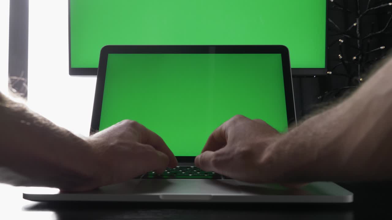 computadora portátil pantalla verde. el hombre está trabajando en la computadora con pantallas de tecla croma, usando los dedos con el teclado para escribir. portátil con pantalla verde en blanco tecla de croma. el macho está usando portátil en la oficina