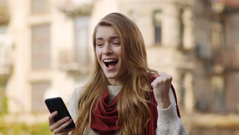 Fröhliche-Frau-Springt-Mit-Telefon.-Aufgeregtes-Mädchen,-Das-Auf-Der-Straße-Auf-Sein-Handy-Schaut.