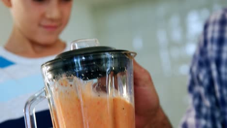 father and son preparing smoothie in kitchen