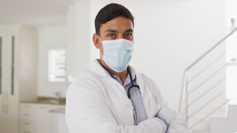 Portrait-of-hispanic-male-doctor-at-home,-all-wearing-face-mask