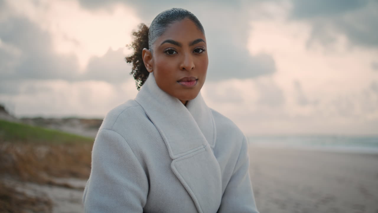 Portrait serious woman look camera at ocean beach. Frustrated pensive model rest