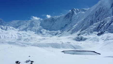 Drone-shot-of-Snowy-land-surrounded-by-mountains-covered-with-snow-in-Manag-Nepal