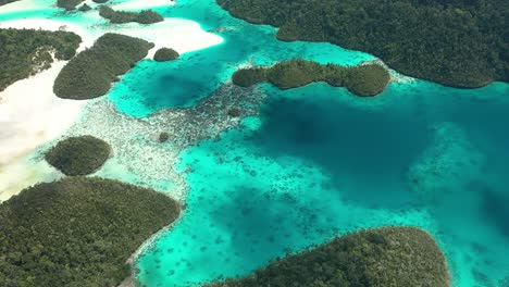 Excellent-Aerial-Shot-Of-The-Wayag-Islands,-Raja-Ampat,-Indonesia,-With-The-Shadows-Of-Passing-Clouds-Visible-In-The-Clear-Blue-Water