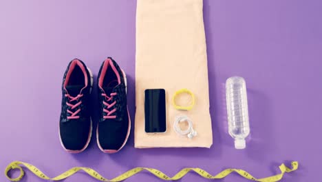 Mobile-phone-with-headphones,-shoes,-water-bottle,-fitness-band,-exercise-mat-and-measuring-tape