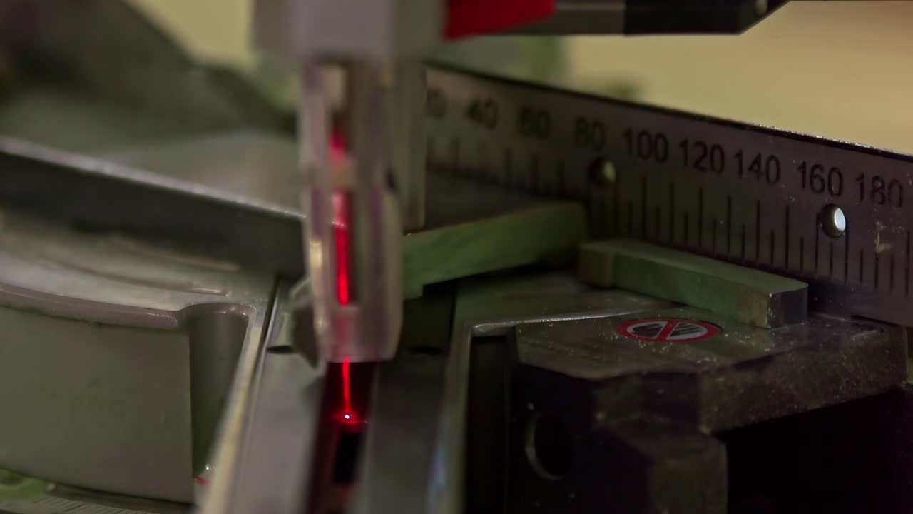 A detailed close-up shows a laser-guided saw precisely cutting a piece of material, highlighting the accuracy and modern cutting technology in a workshop setting