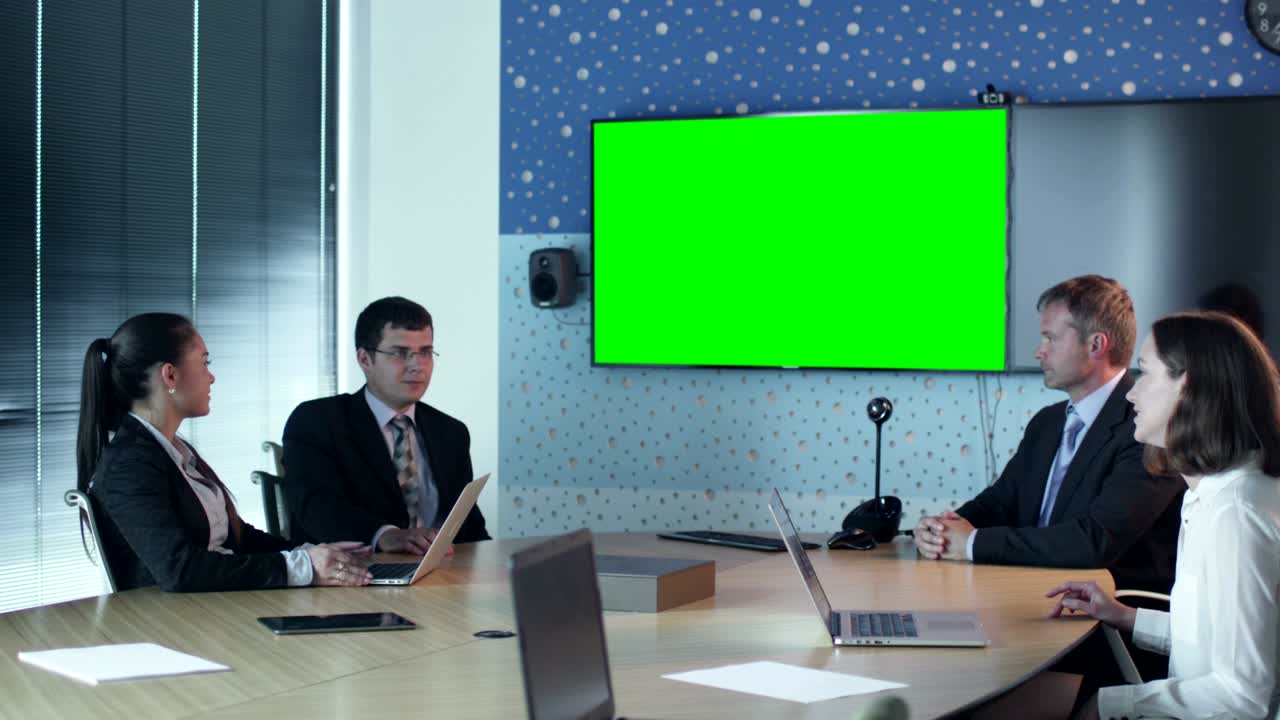 equipo de trabajadores de la oficina tienen conversación en la sala de conferencias. exhibición con pantalla verde para maqueta en la pared.