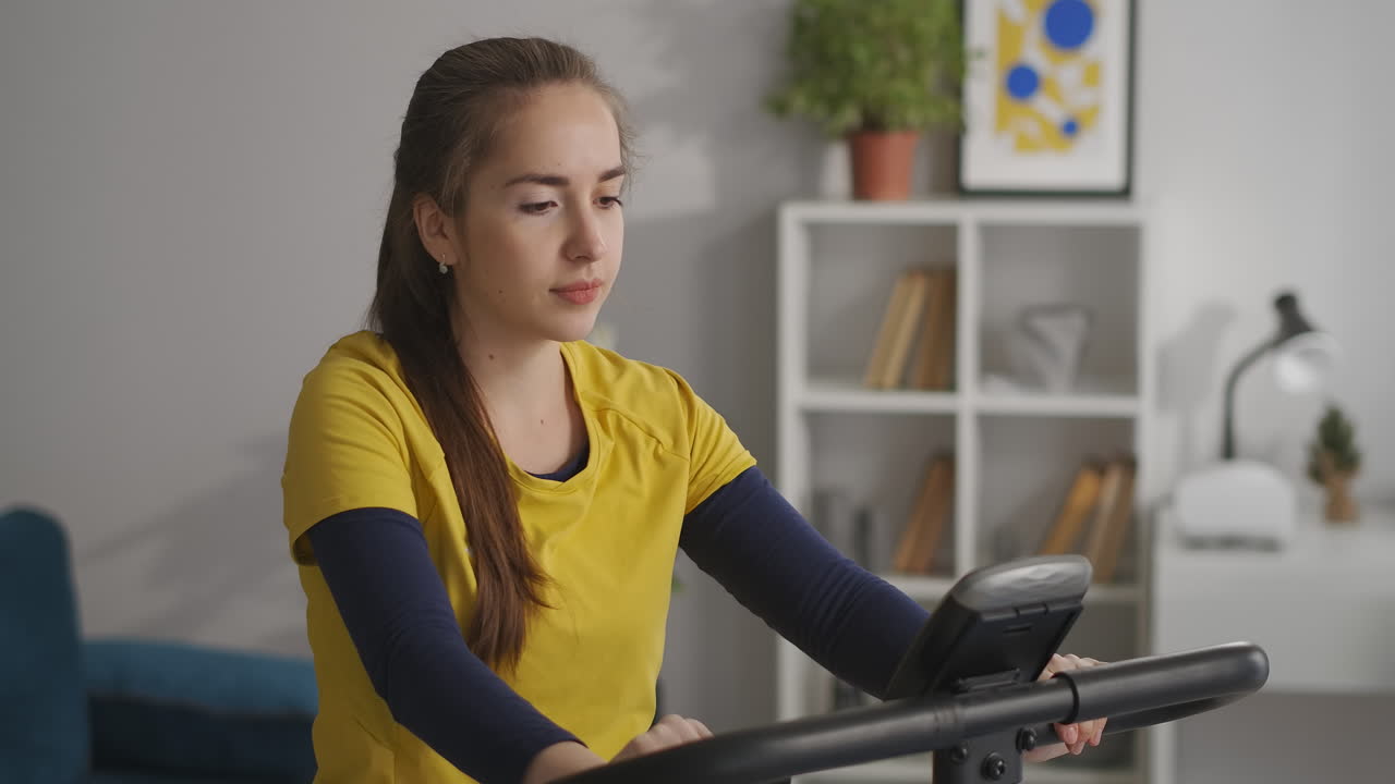 niña de secundaria está entrenando con bicicleta de ejercicio en la sala de estar retrato medio deporte y acondicionamiento físico en el hogar estilo de vida saludable de la juventud moderna