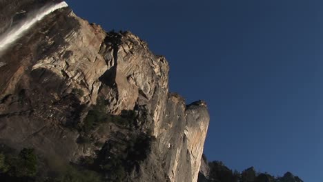 the camera pans left across vertical cliffs to a cascading waterfall