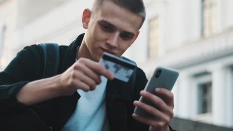 young student guy paying online with credit card.