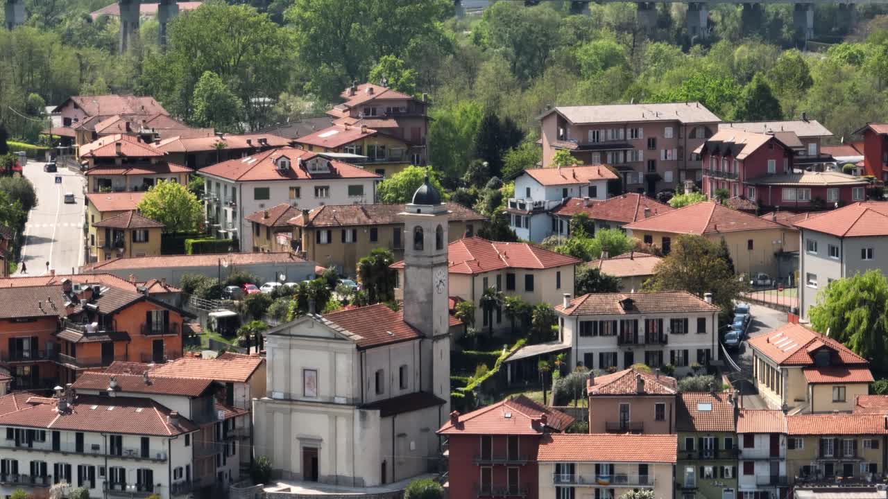 cerca de una pequeña iglesia de pueblo en un pueblo italiano con viejos techos de tejas rojas y exuberantes árboles verdes en la orilla del lago maggiore