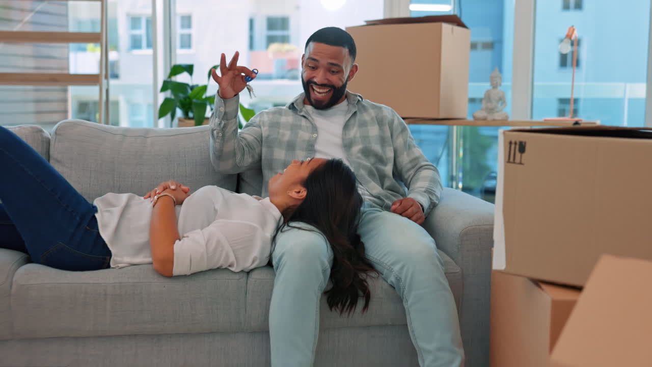 pareja feliz, llaves y relajarse en el sofá en la nueva casa
