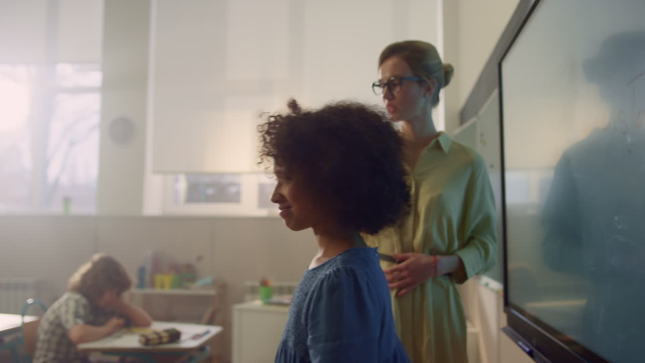 niña de escuela escribiendo en una pizarra digital interactiva. niña afro haciendo una tarea