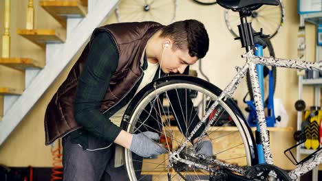 el personal de servicio experimentado está montando la bicicleta ajustando la rueda trasera durante el mantenimiento del vehículo en el lugar de trabajo. instrumentos profesionales, piezas de repuesto y equipos son visibles.