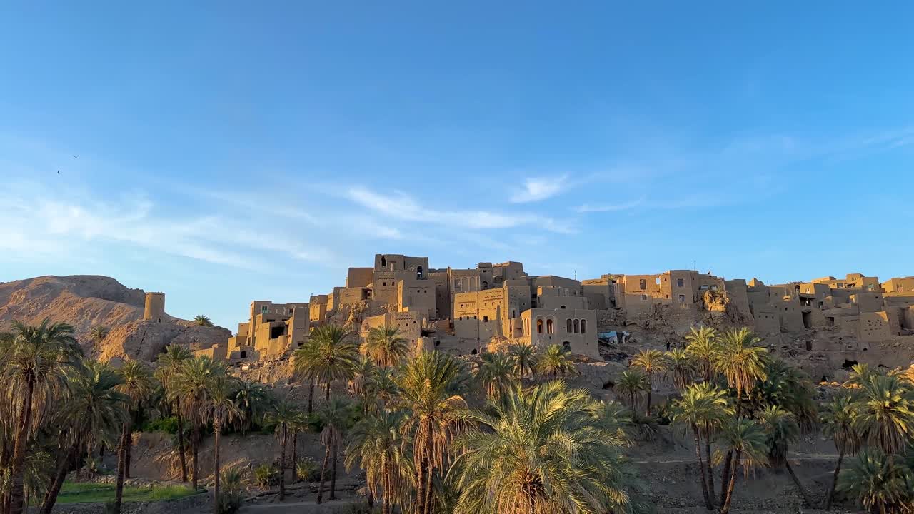Wonderful view of Desert oasis landscape hilltop mud brick clay architecture design house building castle style in Morocco travel destination Date palm garden grove spring season blue sky rural life