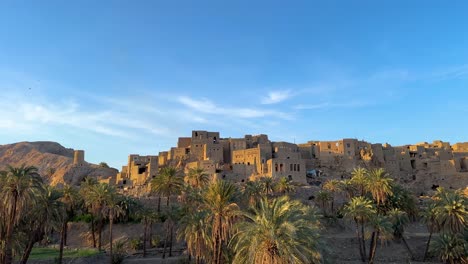 wonderful view of desert oasis landscape hilltop mud brick clay architecture design house building castle style in morocco travel destination date palm garden grove spring season blue sky rural life