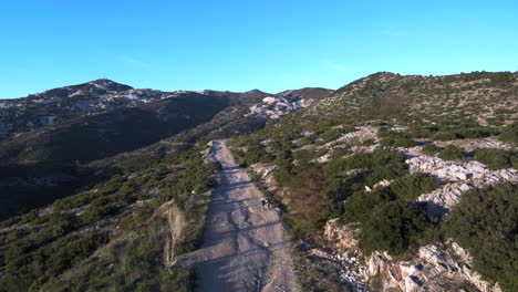 una pareja está caminando por un camino de montaña de grava durante la hora dorada