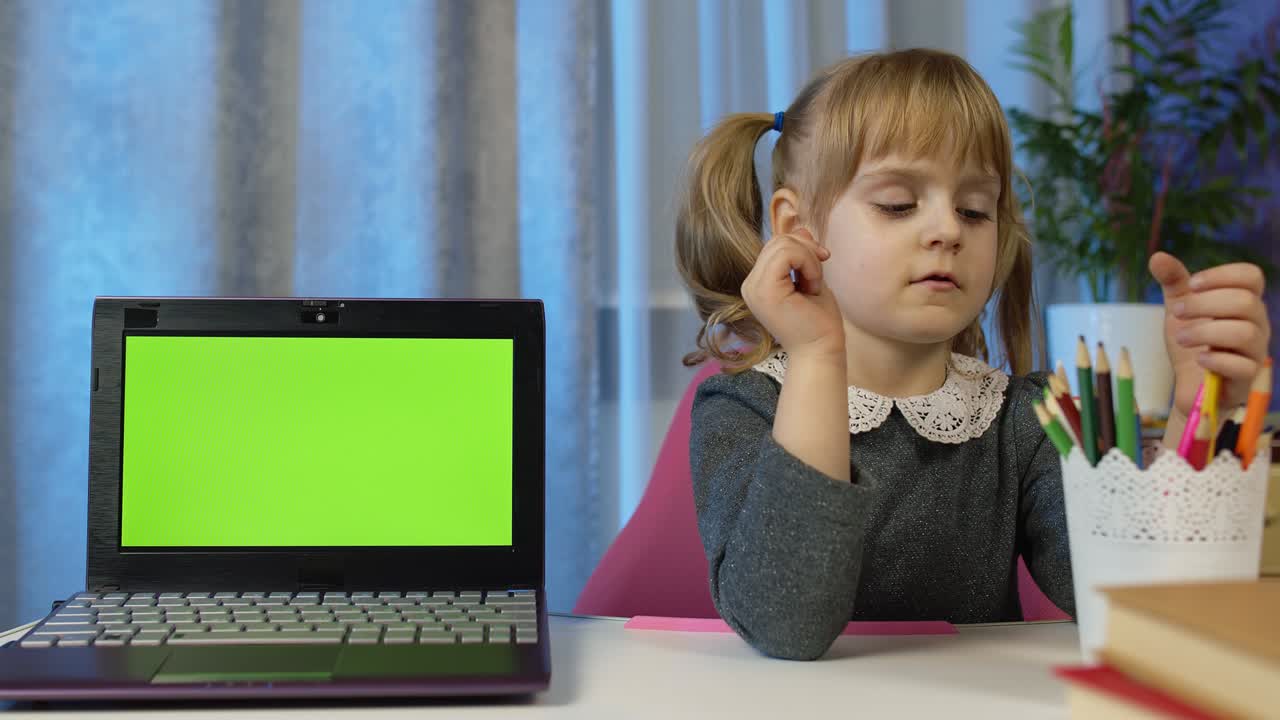 niña estudiante escolar en casa sentada con una computadora portátil digital con tecla de croma de pantalla verde