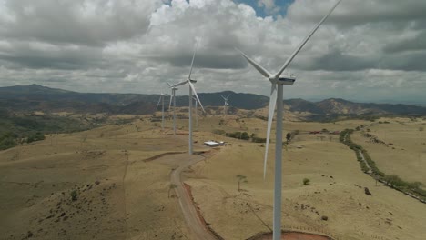 Toma-Panorámica-De-Drones-Alrededor-De-Grandes-Aerogeneradores-Girando-En-El-Viento-En-Un-Día-Nublado