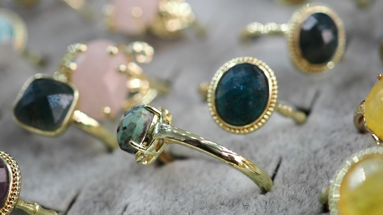 Primer plano de anillos de oro con varias piedras preciosas en exhibición.