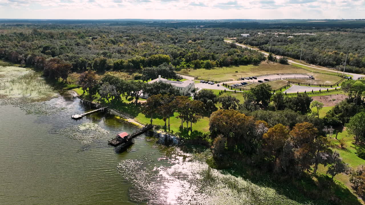 Vista aérea panorámica con dron del espacio para bodas Bella Cosa en Lake Wales, Florida, que muestra su finca junto al lago y su exuberante entorno rural