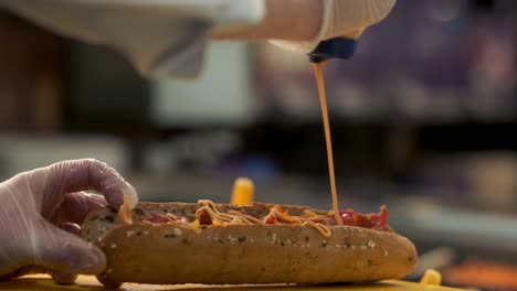 Chipotle-sauce-being-poured-over-a-sandwich-bread-roll-in-a-deli-slow-motion-shot