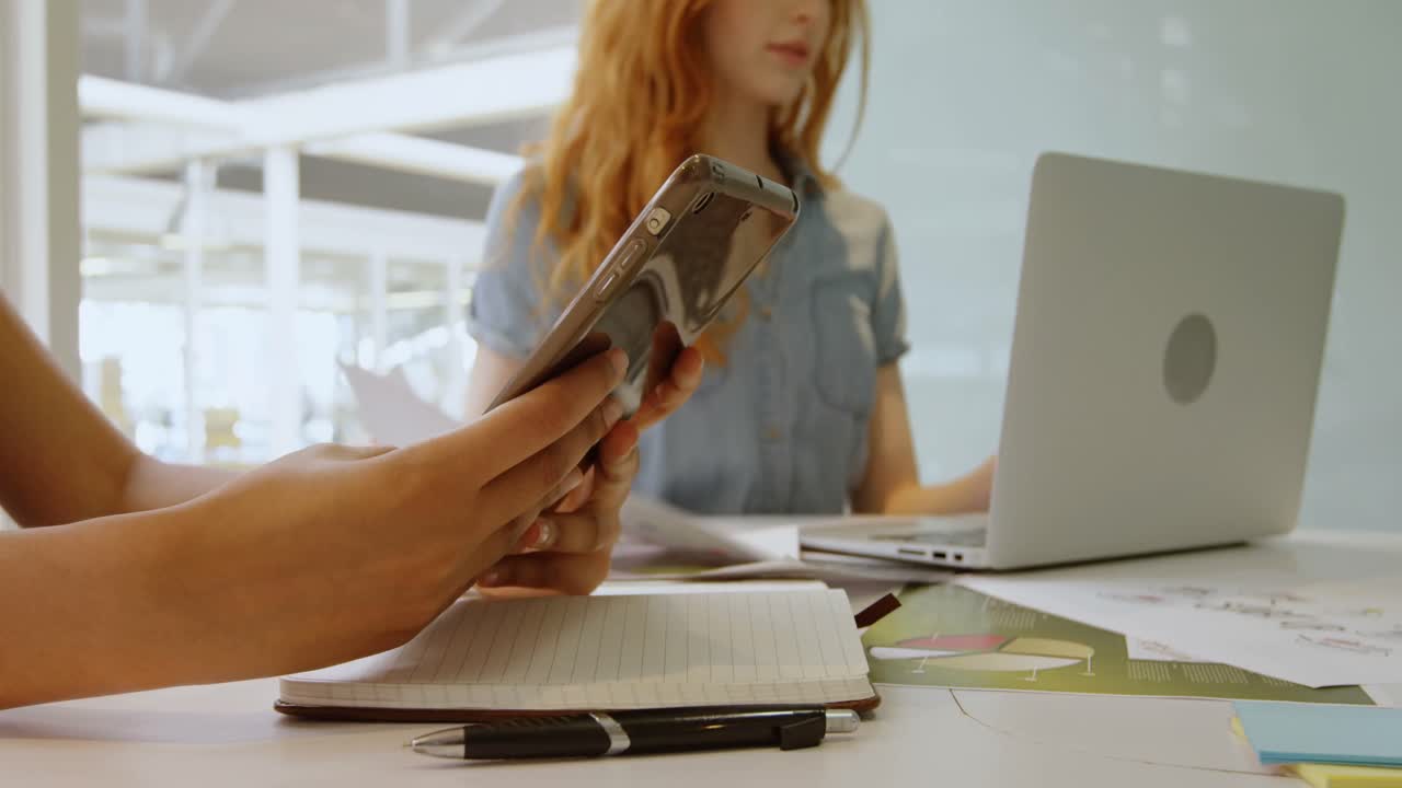 руководители, использующие мобильные телефоны и ноутбуки в офисе 4k