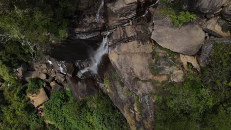 Después-De-Una-Larga-Caminata-Por-El-Borde-De-La-Cascada-De-Hojas-De-Los-Amantes-Más-Altos,-Varios-Turistas-Miran-El-Agua-Que-Cae-Sobre-Las-Rocas-Talladas-Entre-La-Naturaleza-De-Sri-lanka